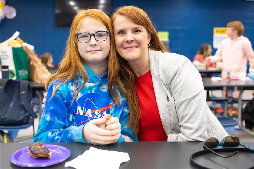 Creekside Elementary students eat donuts with a grown-up